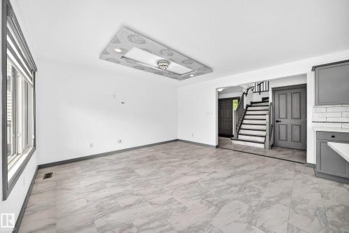 Open-concept living space featuring light-toned tile flooring, recessed lighting, a decorative ceiling fixture, and a window with blinds - 1549 37C Avenue, Edmonton, AB 