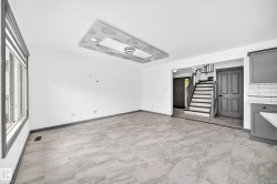 Open-concept living space featuring light-toned tile flooring, recessed lighting, a decorative ceiling fixture, and a window with blinds - 