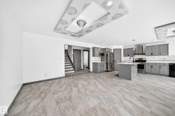Open-concept living space featuring a contemporary kitchen with gray cabinetry, white subway tile backsplash, and stainless steel appliances - 