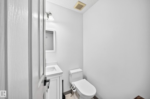 Compact powder room featuring a white single-sink vanity with a countertop and under-sink cabinetry - 1549 37C Avenue, Edmonton, AB 