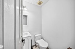 Compact powder room featuring a white single-sink vanity with a countertop and under-sink cabinetry - 
