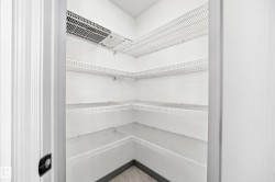 Corner pantry featuring multiple levels of wire shelving, white wall finishes, and a dark baseboard trim - 