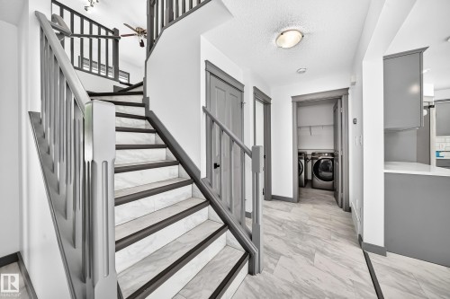 Curved staircase featuring dark-stained wood-finish railings and white marble-look risers with dark-stained wood-finish treads - 1549 37C Avenue, Edmonton, AB 