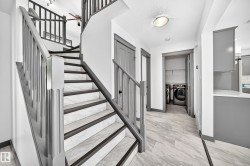 Curved staircase featuring dark-stained wood-finish railings and white marble-look risers with dark-stained wood-finish treads - 