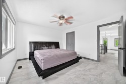 Spacious room featuring light-toned flooring, white walls, and a ceiling fan with integrated lighting - 