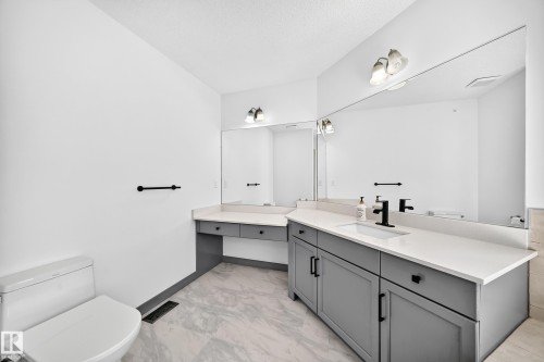 Bathroom featuring a double vanity with grey cabinetry, white countertops, and integrated rectangular sinks - 1549 37C Avenue, Edmonton, AB 
