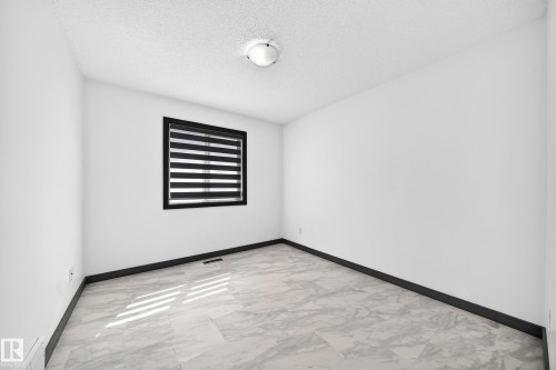 Neutral white walls with contrasting dark trim and window frame, complemented by a contemporary window treatment - 1549 37C Avenue, Edmonton, AB 