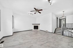 Spacious room featuring light-toned tile flooring, a fireplace with a light-toned stone surround, and a dark wood mantel - 