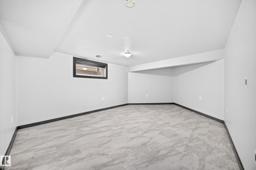 Spacious interior featuring light gray walls, dark trim, and patterned flooring - 1549 37C Avenue, Edmonton, AB 