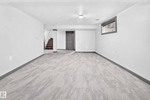 Spacious open room featuring light-toned large format tile flooring, crisp white walls, and a recessed window - 1549 37C Avenue, Edmonton, AB 
