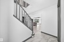 Hallway entrance featuring marble-look tile flooring and a gray-painted staircase with vertical balusters - 1549 37C Avenue, Edmonton, AB 