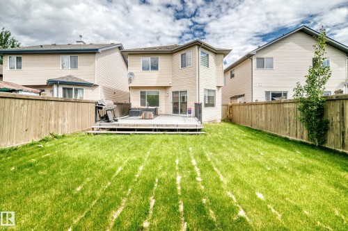 Expansive rear yard featuring a large wooden deck, sliding glass door access, and a fully fenced perimeter - 1549 37C Avenue, Edmonton, AB 