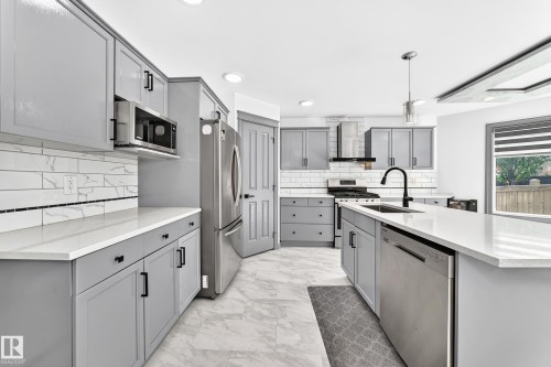 Modern kitchen featuring grey cabinetry, white countertops, stainless steel appliances, and a tile backsplash - 1549 37C Avenue, Edmonton, AB 