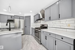 Kitchen featuring gray cabinetry with black hardware, white countertops, stainless steel appliances, and wood-finish flooring - 