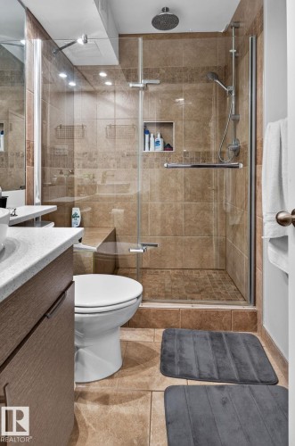 Glass-enclosed shower featuring a built-in bench, rain showerhead, handheld shower fixture, and recessed niche - G14 10148 118 Street Nw, Edmonton, AB 