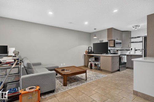 Open-concept living area featuring tile flooring, recessed lighting, and a kitchen with stainless steel appliances, shaker-style cabinetry, and white subway tile backsplash - G14 10148 118 Street Nw, Edmonton, AB 