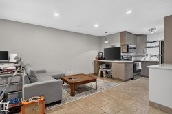 Open-concept living area featuring tile flooring, recessed lighting, and a kitchen with stainless steel appliances, shaker-style cabinetry, and white subway tile backsplash - 