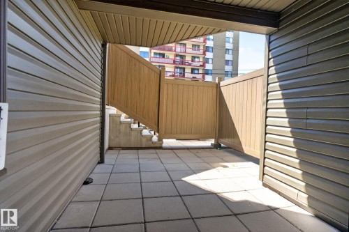 Private patio space featuring light gray square pavers and wood-look fencing - G14 10148 118 Street Nw, Edmonton, AB 