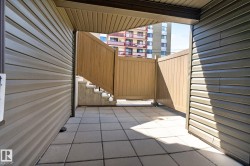 Private patio space featuring light gray square pavers and wood-look fencing - 