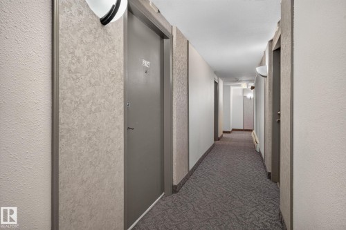 Corridor featuring patterned carpeting, textured wall coverings, and flush-mounted light fixtures - G14 10148 118 Street Nw, Edmonton, AB 