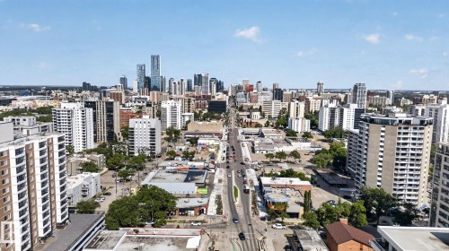Cityscape featuring a prominent downtown skyline, diverse architectural styles, a central thoroughfare, and mature trees interspersed throughout the urban landscape - G14 10148 118 Street Nw, Edmonton, AB 