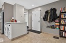 Entryway featuring tile flooring, a built-in laundry station with stacked appliances, and a solid entry door - G14 10148 118 Street Nw, Edmonton, AB 