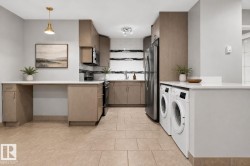 Combined kitchen and laundry area featuring light-toned cabinetry, stainless steel appliances, a tile backsplash, and neutral tile flooring - 