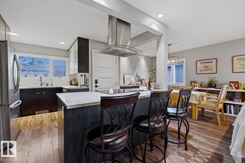 Open-concept kitchen featuring stainless steel appliances and an island with room for seating - 10328 73 Street, Edmonton, AB 