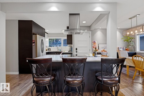 Open-concept kitchen featuring stainless steel appliances and an island with room for seating - 10328 73 Street, Edmonton, AB 