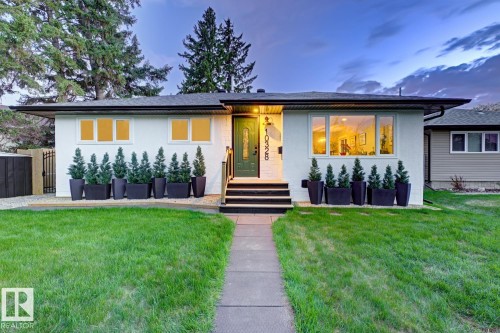 White stucco exterior with black trim, presenting a prominent, modern front entrance with a dark green door and low maintenance landscaping - 10328 73 Street, Edmonton, AB 