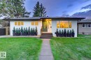 White stucco exterior with black trim, presenting a prominent, modern front entrance with a dark green door and low maintenance landscaping - 10328 73 Street, Edmonton, AB 