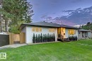 White stucco exterior with black trim, presenting a prominent, modern front entrance with a dark green door and low maintenance landscaping - 10328 73 Street, Edmonton, AB 
