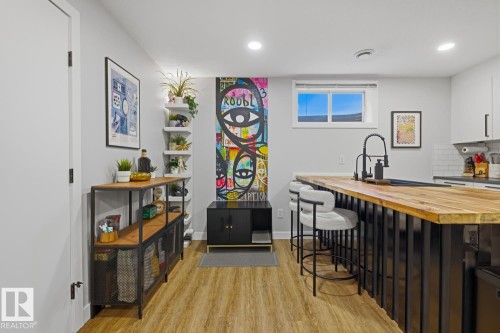 Contemporary basement suite kitchen featuring an expansive island with room for seating, butcher block countertop, black finishes/faucet and stainless steel appliances - 10328 73 Street, Edmonton, AB 