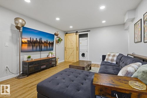 Well lit, open-concept living space with recessed lighting and barn doors for in-suite stacking laundry as well as primary basement bedroom - 10328 73 Street, Edmonton, AB 