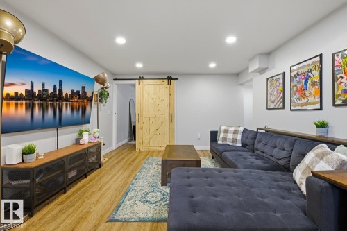 Well lit, open-concept living space with recessed lighting and barn doors for in-suite stacking laundry as well as primary basement bedroom - 10328 73 Street, Edmonton, AB 