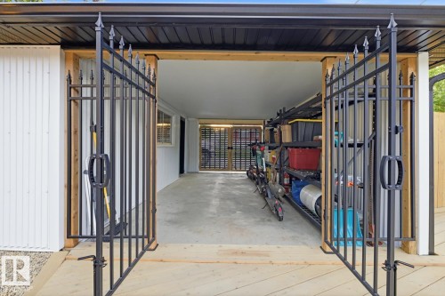 Gated carport featuring wrought iron dual entry gates with finial detailing and an additional locked security gate at the driveway/alley - 10328 73 Street, Edmonton, AB 