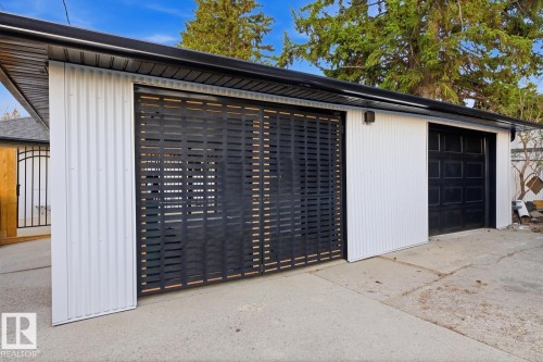 Detached single-car garage & single-carport from the driveway/alley, featuring modern white and black finishes and accents - 10328 73 Street, Edmonton, AB 