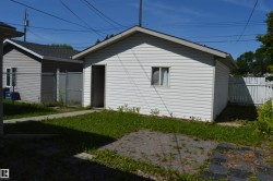 Detached garage with white siding and an asphalt shingle roof - 