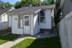 White siding exterior with an attached entryway featuring a glass-paneled door, a single-pane window, and an exterior wall sconce - 