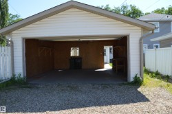 Detached two-car garage with white vinyl siding and an asphalt shingle roof - 