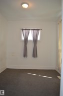Room featuring a flush mount ceiling light, a window with existing curtain rods, and dark gray carpeting - 