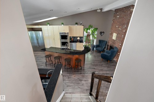 Open-concept living area featuring a kitchen with light wood cabinetry, a large kitchen island with dark countertops, and stainless steel appliances - 4 Wentworth Crescent, St. Albert, AB 
