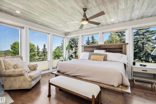 Spacious room featuring multiple large windows, wood-finish flooring, a wood-paneled ceiling, a ceiling fan with integrated lighting, and a rustic wood headboard - 4 Wentworth Crescent, St. Albert, AB 