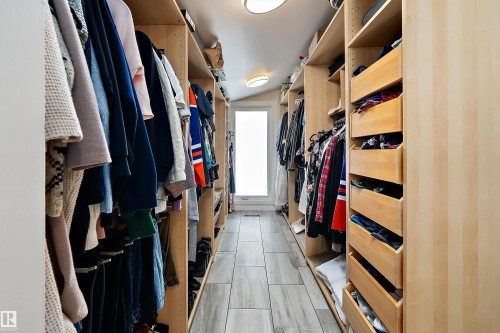 Spacious walk-in closet featuring extensive built-in light wood cabinetry, multiple hanging rods, integrated drawers, and a light wood-finish flooring - 4 Wentworth Crescent, St. Albert, AB 