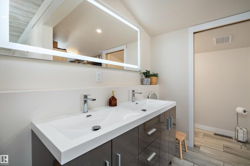 Dual basin vanity with integrated white countertop, chrome fixtures, and illuminated mirror - 4 Wentworth Crescent, St. Albert, AB 
