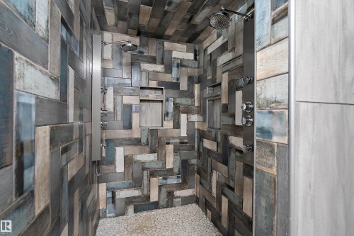 Shower featuring multicolored wood-finish tile walls, dual shower heads, dual shower panel systems, two recessed niches, and a pebble stone floor - 4 Wentworth Crescent, St. Albert, AB 