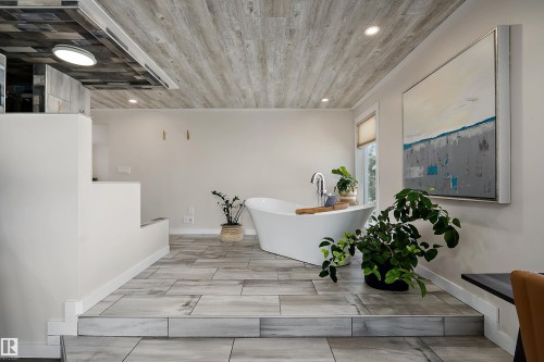 Freestanding soaking tub with floor-mounted faucet in a space featuring plank-style ceiling treatment, recessed lighting, and large format floor tile - 4 Wentworth Crescent, St. Albert, AB 