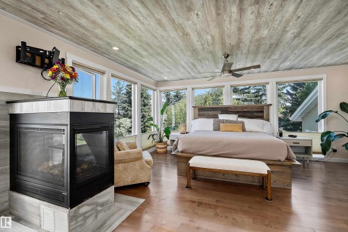 Room featuring a corner fireplace with a tile surround, wood-finish flooring, and expansive windows - 4 Wentworth Crescent, St. Albert, AB 