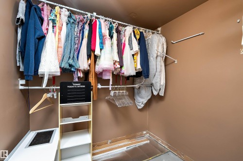 Closet featuring a multi-tiered hanging rod system, light brown wall color, and a built-in shelving unit - 4 Wentworth Crescent, St. Albert, AB 