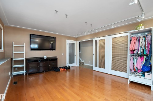 Hardwood flooring throughout a spacious room featuring track lighting and a built-in entertainment console - 4 Wentworth Crescent, St. Albert, AB 